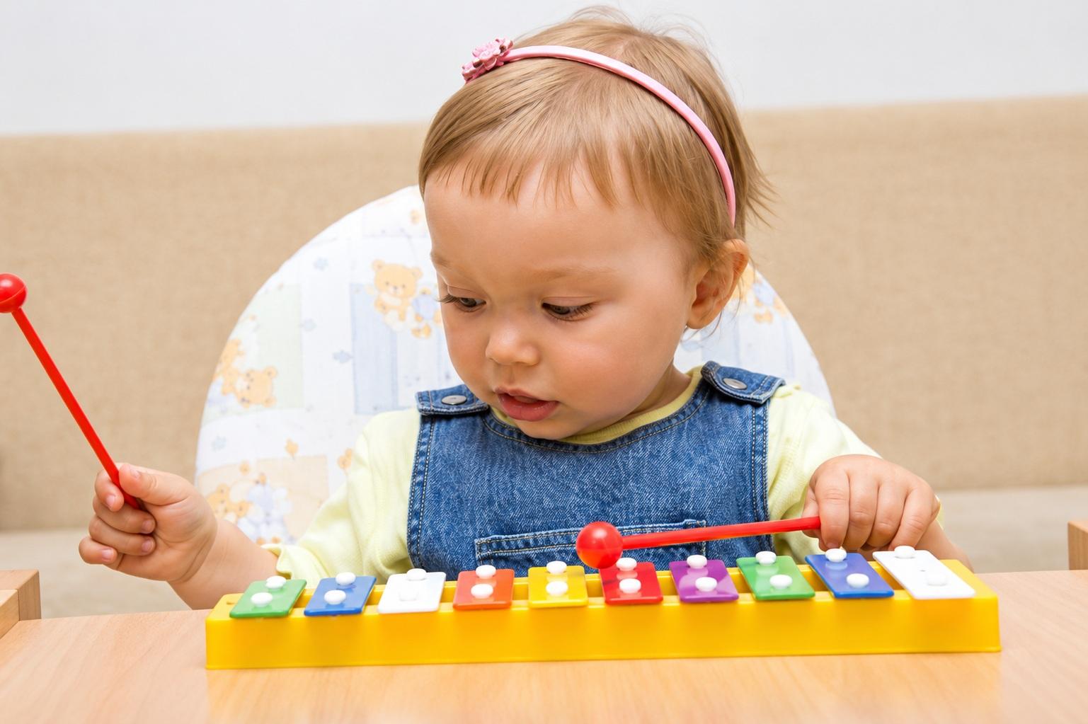 Young child exploring a colourful toy xylophone